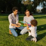 Family playing ring toss together enjoying sunny day in park.
