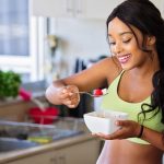 Cheerful woman enjoying fresh strawberries in a cozy kitchen setting. Promotes healthy living and happiness.